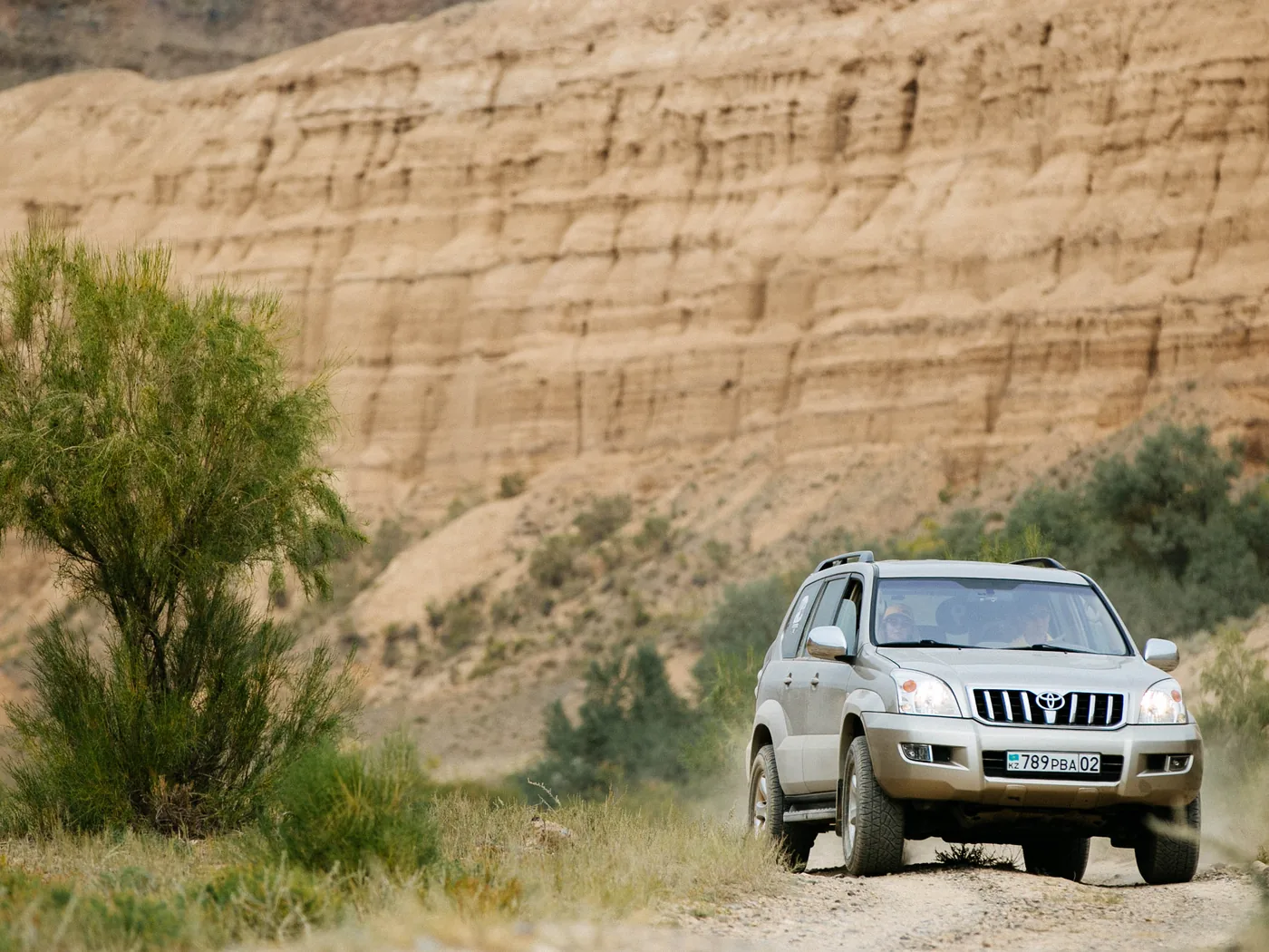 A Land Cruiser Prado driving on a dirt road through a canyon